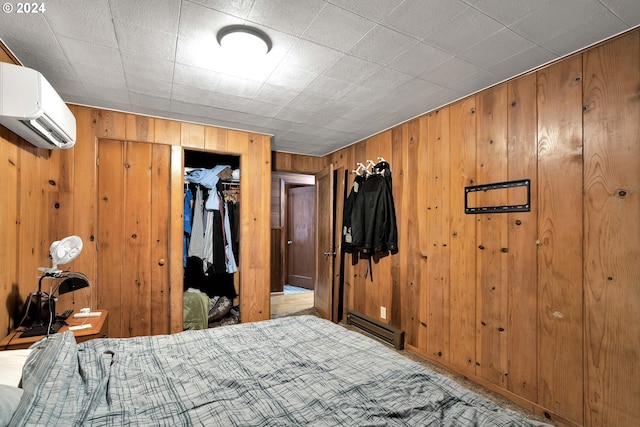 bedroom featuring wood walls, a baseboard radiator, a closet, and a wall mounted air conditioner