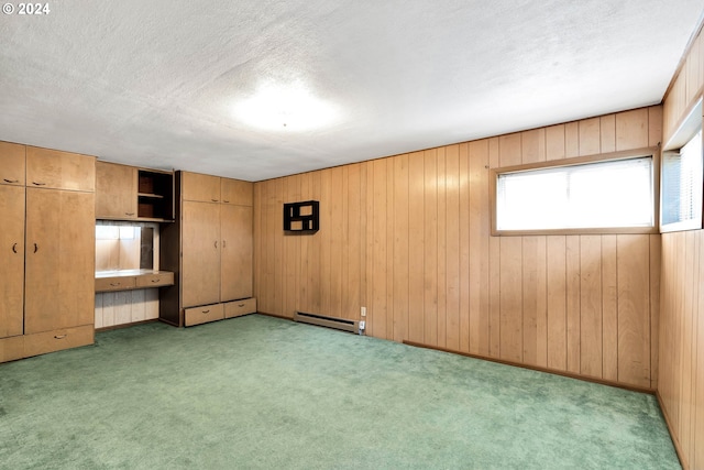 unfurnished bedroom with a textured ceiling, built in desk, baseboard heating, and light colored carpet