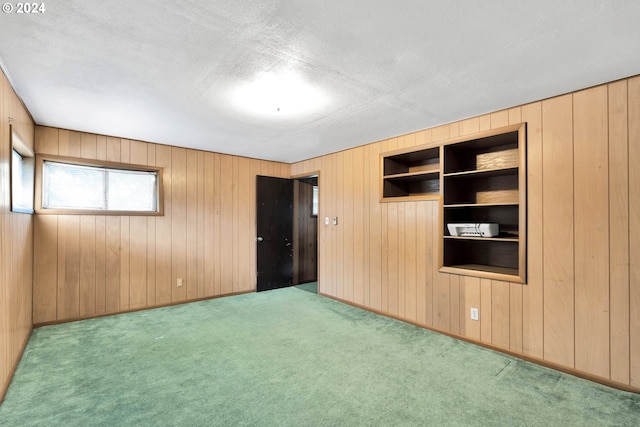 unfurnished bedroom with light carpet, wood walls, a textured ceiling, and baseboards