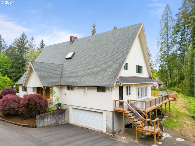 view of front of property featuring an attached garage, a shingled roof, stairs, a chimney, and aphalt driveway