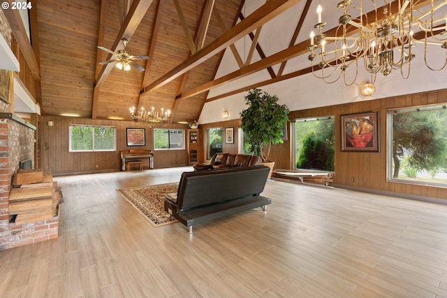 living room with light hardwood / wood-style flooring, wood walls, ceiling fan with notable chandelier, and high vaulted ceiling