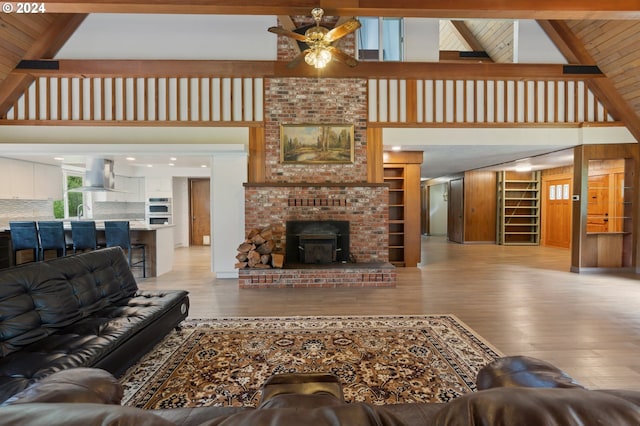 living room with a fireplace, wood-type flooring, beam ceiling, and ceiling fan