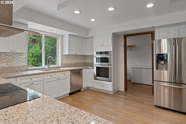 kitchen with white cabinets, light hardwood / wood-style flooring, light stone counters, stainless steel appliances, and sink