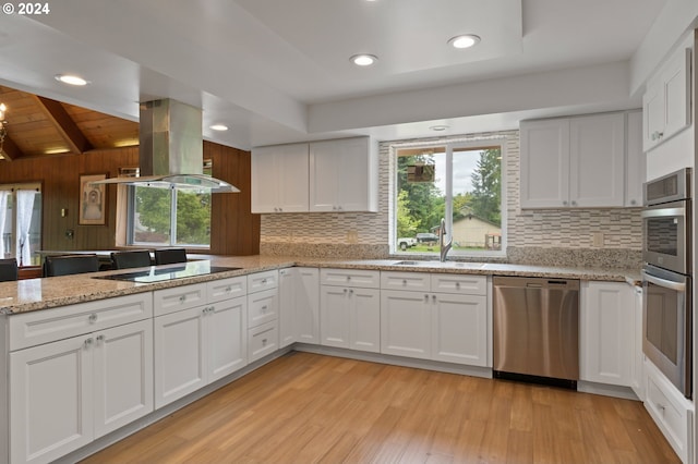 kitchen featuring white cabinets, stainless steel appliances, light hardwood / wood-style floors, island range hood, and vaulted ceiling with beams