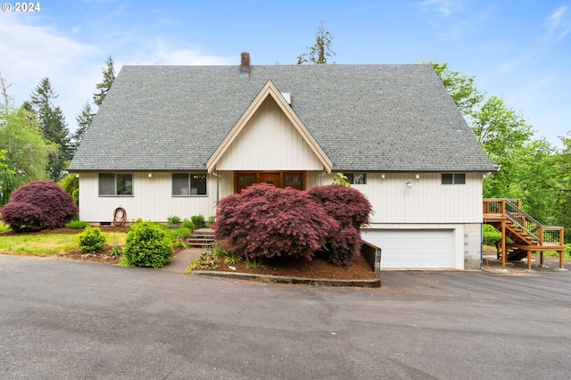 view of front of house featuring stairway, driveway, a shingled roof, and a garage