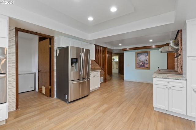 kitchen with light wood-type flooring, light stone countertops, stainless steel appliances, and white cabinetry