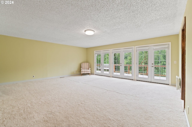 carpeted empty room featuring french doors and a textured ceiling