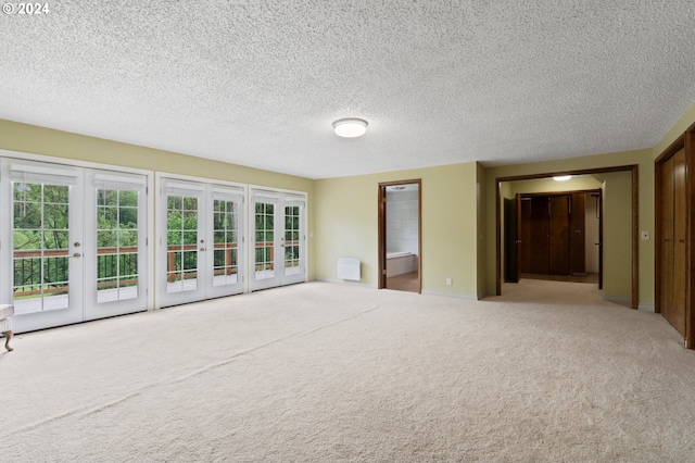 unfurnished room featuring light carpet, french doors, and a textured ceiling