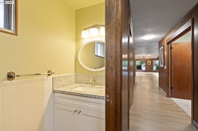 bathroom with wood-type flooring, vanity, and a textured ceiling