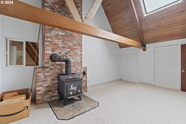 carpeted living room with a wood stove, beamed ceiling, high vaulted ceiling, and a skylight