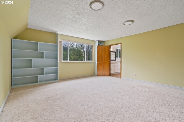 carpeted empty room featuring lofted ceiling and a textured ceiling