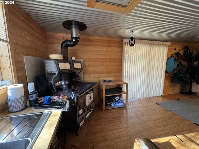 kitchen featuring wooden walls, a wood stove, and hardwood / wood-style flooring