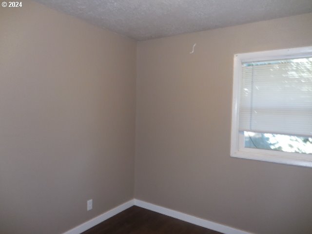 spare room with a textured ceiling and dark hardwood / wood-style flooring