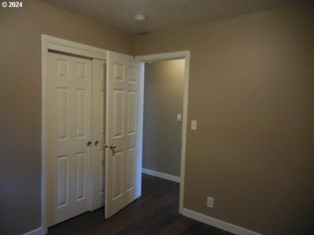 unfurnished bedroom featuring a closet and dark wood-type flooring