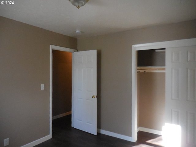 unfurnished bedroom featuring a closet and dark hardwood / wood-style flooring