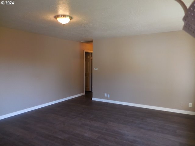 unfurnished room featuring a textured ceiling and dark wood-type flooring