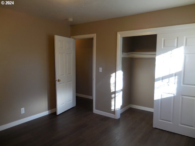 unfurnished bedroom featuring a closet and dark hardwood / wood-style floors