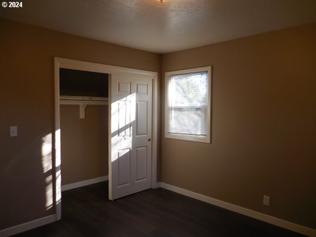 unfurnished bedroom with dark hardwood / wood-style floors and a closet