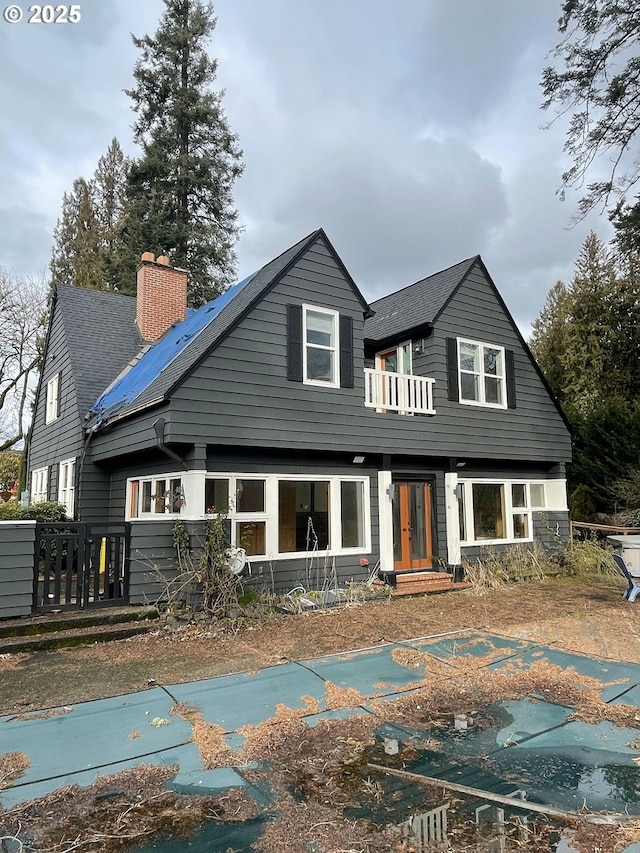 back of property with entry steps, roof with shingles, and a chimney