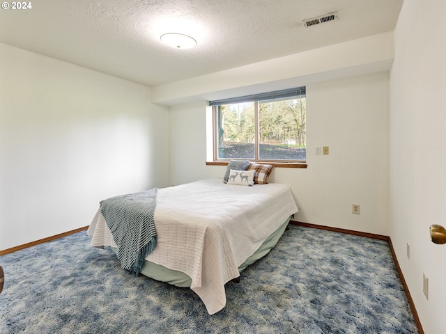 bedroom featuring dark carpet and a textured ceiling