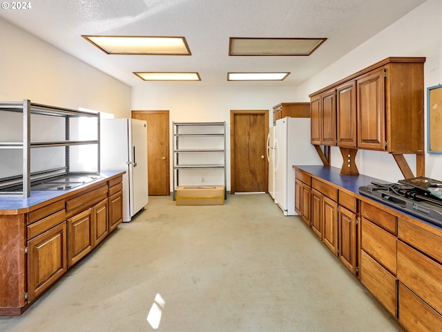 kitchen with a textured ceiling, white refrigerator, and stainless steel gas cooktop