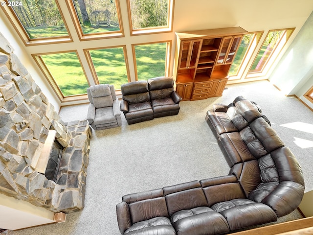 carpeted living room featuring a high ceiling, a healthy amount of sunlight, and a fireplace