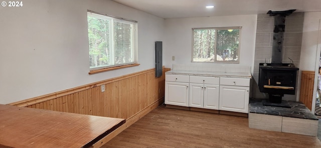 interior space featuring white cabinets, light hardwood / wood-style flooring, and a wood stove