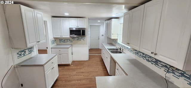 kitchen with white cabinets, light hardwood / wood-style flooring, and sink