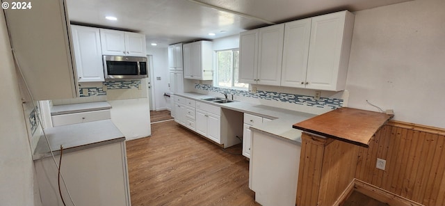 kitchen with white cabinets, sink, light hardwood / wood-style floors, and tasteful backsplash