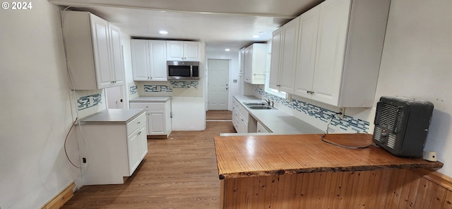 kitchen featuring white cabinets, stainless steel appliances, light hardwood / wood-style floors, and backsplash