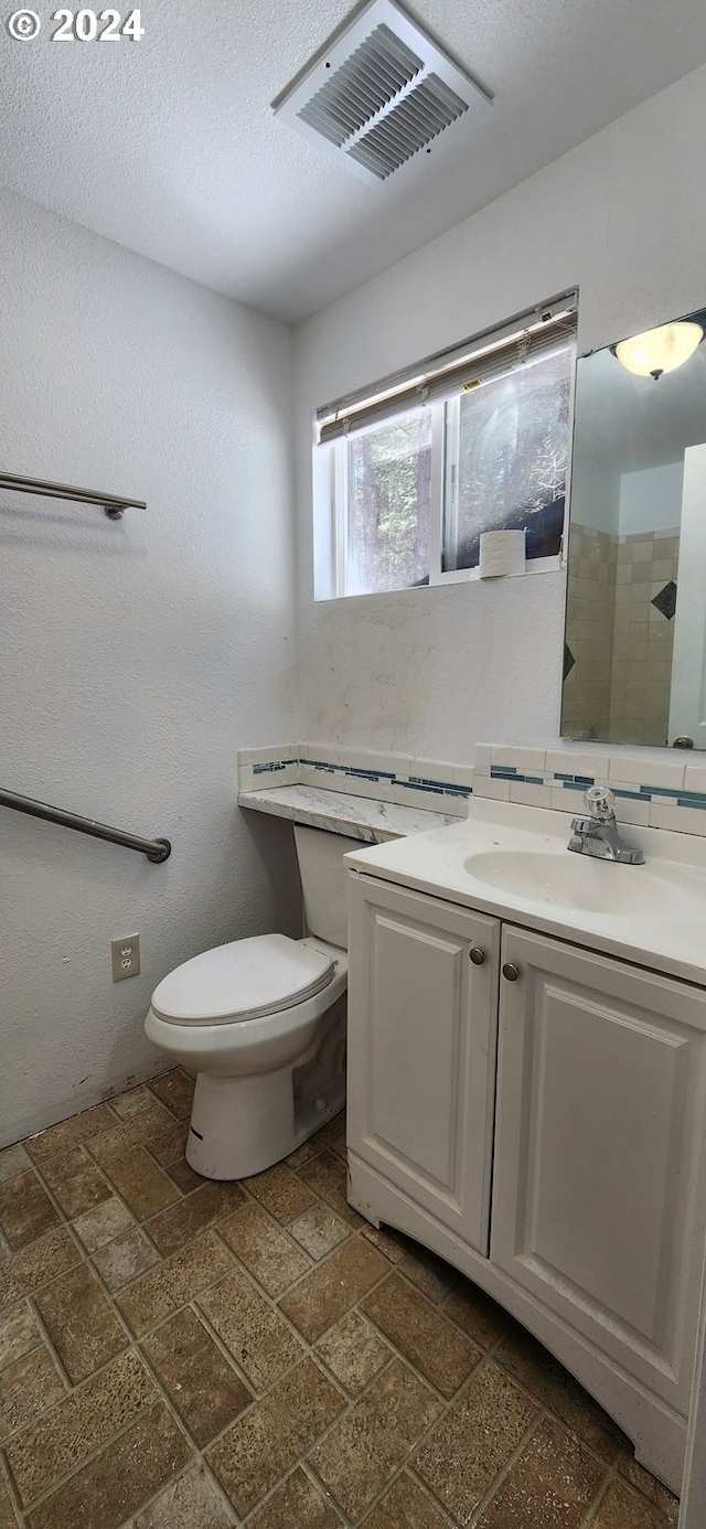 bathroom featuring tile flooring, large vanity, a textured ceiling, backsplash, and toilet