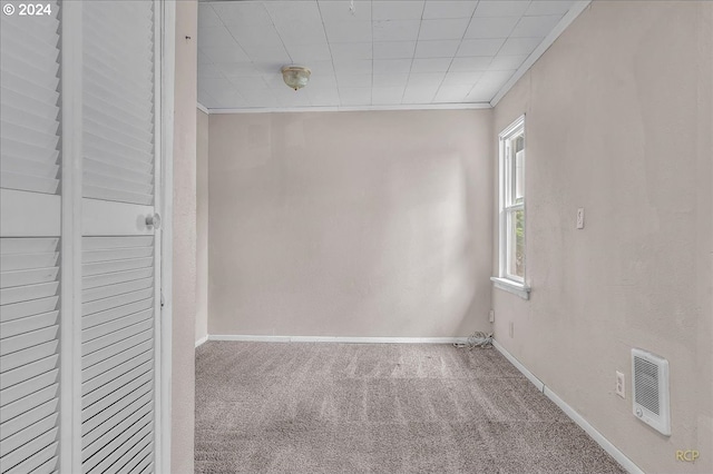 carpeted spare room with heating unit and ornamental molding