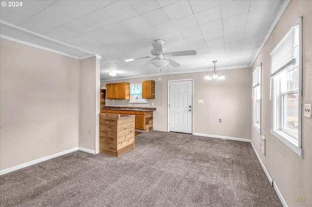 unfurnished living room with carpet, sink, ceiling fan with notable chandelier, and crown molding