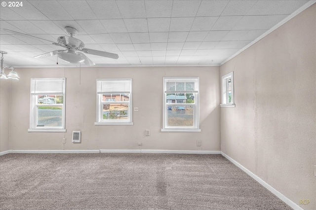 empty room featuring heating unit, ceiling fan, ornamental molding, and carpet flooring