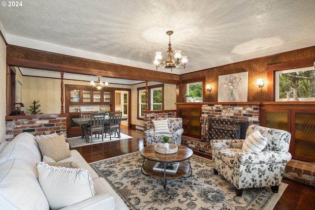 living room featuring a notable chandelier, a healthy amount of sunlight, wood-type flooring, and a brick fireplace