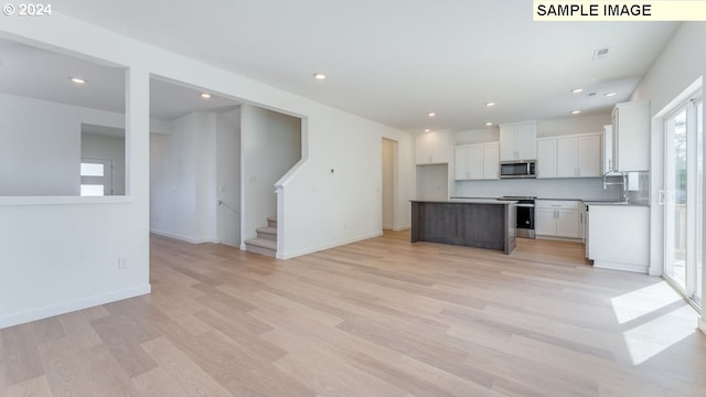 kitchen featuring stainless steel appliances, backsplash, a center island, white cabinets, and light hardwood / wood-style floors