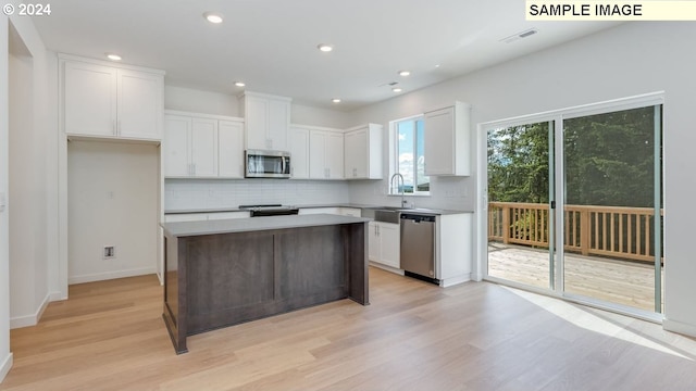 kitchen featuring a kitchen island, white cabinetry, light wood-type flooring, sink, and stainless steel appliances