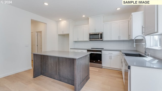 kitchen featuring sink, a center island, white cabinets, appliances with stainless steel finishes, and light hardwood / wood-style floors