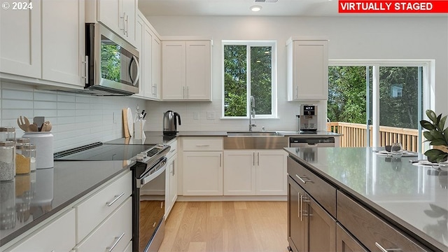 kitchen featuring sink, appliances with stainless steel finishes, light wood-type flooring, and white cabinets