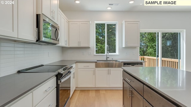 kitchen featuring sink, white cabinets, stainless steel appliances, and light hardwood / wood-style floors