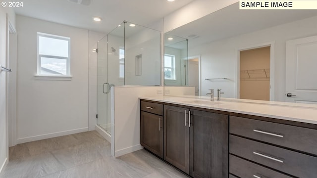 bathroom featuring a shower with door and vanity