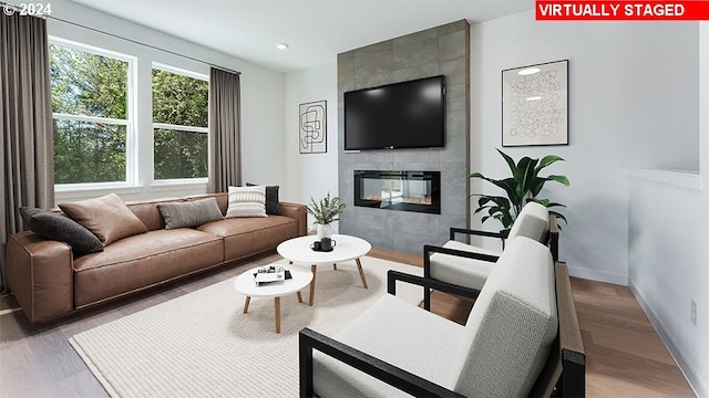 living room with a tiled fireplace and wood-type flooring