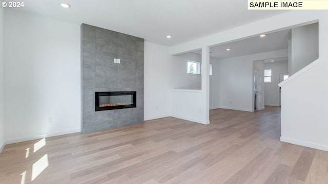 unfurnished living room featuring light hardwood / wood-style floors, a healthy amount of sunlight, and a tiled fireplace