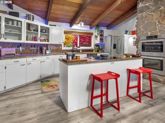 kitchen with white cabinetry, sink, a breakfast bar area, vaulted ceiling with beams, and stainless steel appliances