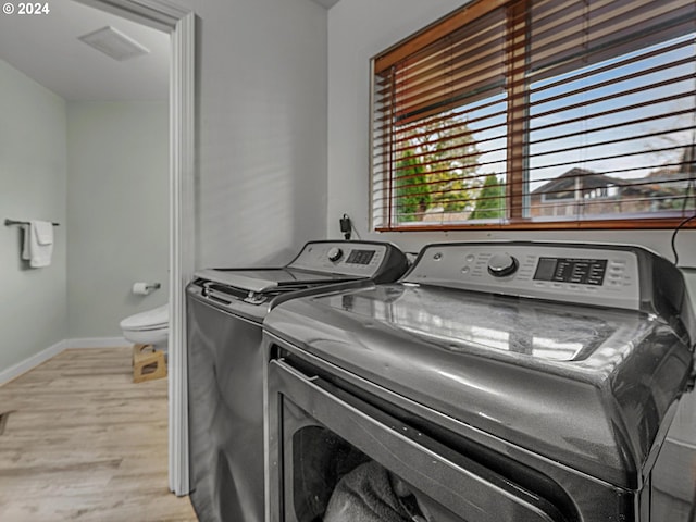 laundry area with light hardwood / wood-style flooring and washer and clothes dryer