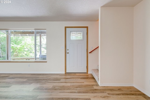 foyer entrance featuring light hardwood / wood-style flooring and a textured ceiling