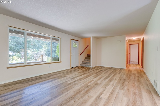 unfurnished living room featuring light hardwood / wood-style floors and a textured ceiling