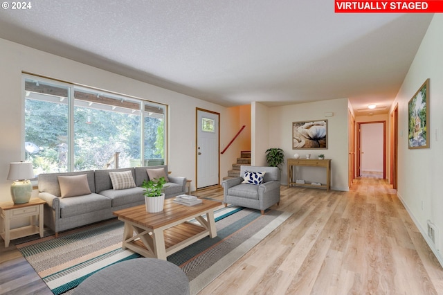 living room with a textured ceiling and light wood-type flooring