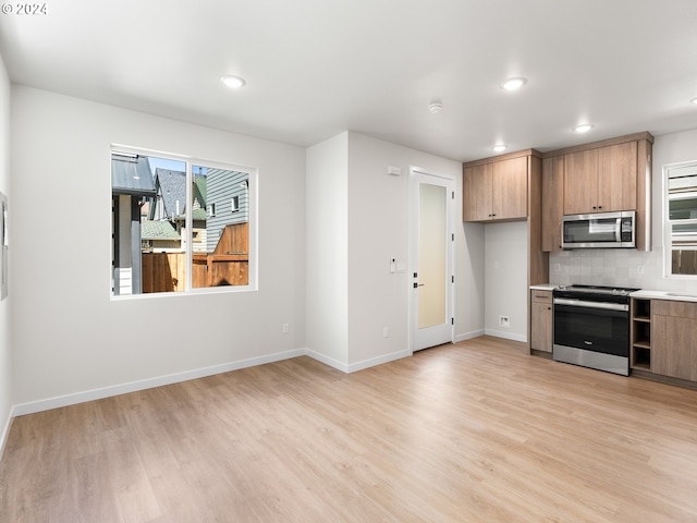 kitchen with backsplash, light hardwood / wood-style flooring, and appliances with stainless steel finishes