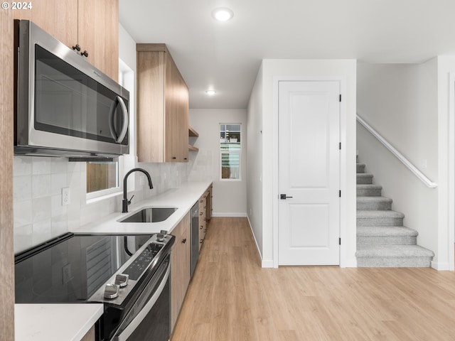 kitchen featuring tasteful backsplash, sink, stainless steel appliances, and light wood-type flooring